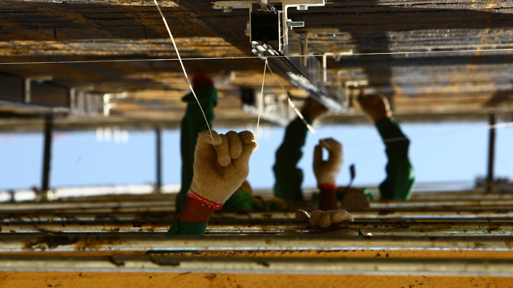 Only hands with gloves made of knitted wool are seen sticking out from behind iron walls.